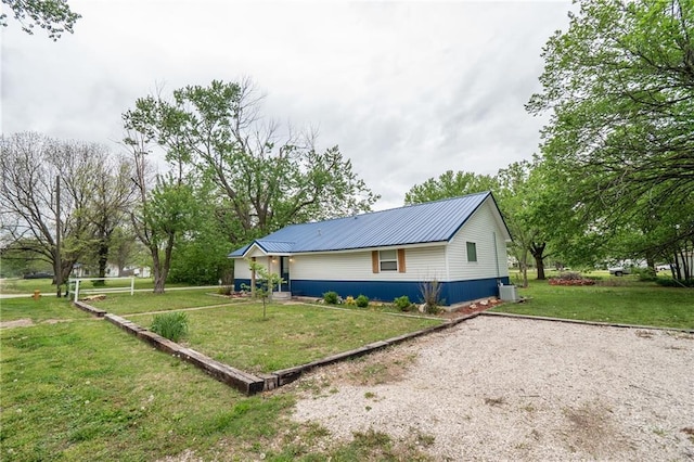view of home's exterior featuring metal roof, a lawn, and gravel driveway