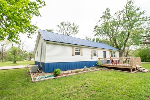 back of house featuring metal roof, a deck, a yard, and central AC unit