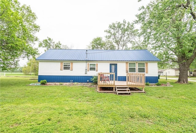 back of property with metal roof, a deck, and a yard