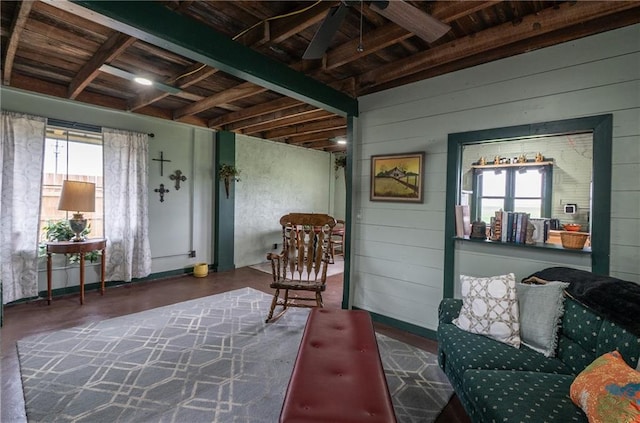 sitting room with wood walls, ceiling fan, and plenty of natural light