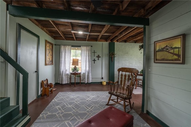 sitting room with wood walls, wooden ceiling, and stairs