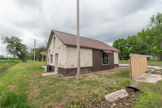 view of side of home with metal roof and a lawn