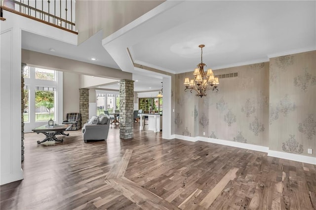 25203 W 97th Ter, Lenexa, KS 66227 - living room with decorative columns, a chandelier, wood finished floors, wallpapered walls, and baseboards