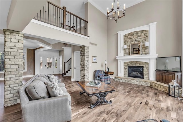 25203 W 97th Ter, Lenexa, KS 66227 - living room with ornate columns, wood finished floors, a chandelier, a fireplace, and stairway