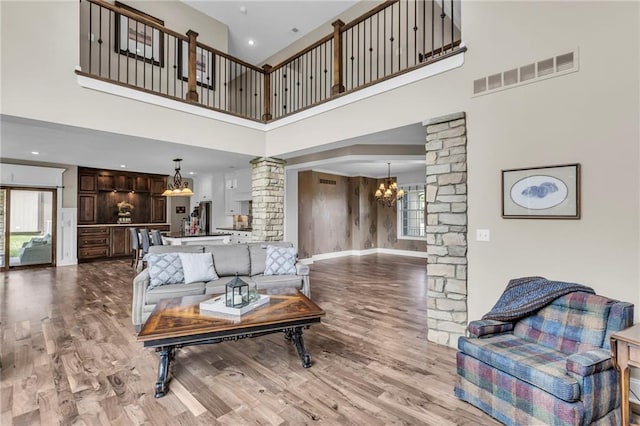 25203 W 97th Ter, Lenexa, KS 66227 - living area featuring ornate columns, a towering ceiling, a chandelier, plenty of natural light, and wood finished floors