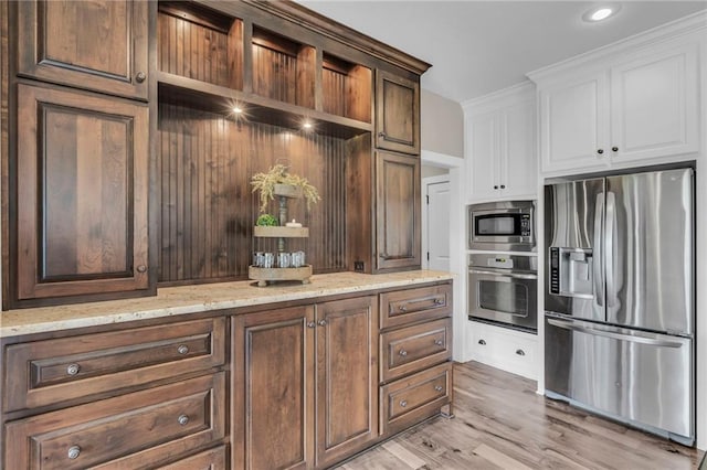 25203 W 97th Ter, Lenexa, KS 66227 - kitchen with stainless steel appliances, white cabinetry, light stone countertops, and light wood-style floors