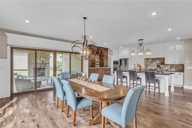 25203 W 97th Ter, Lenexa, KS 66227 - dining space featuring a chandelier, light wood-style floors, a fireplace, and recessed lighting