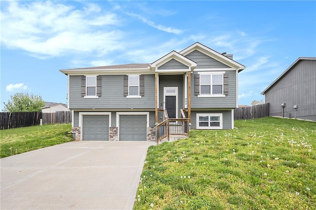 raised ranch with a garage, fence, concrete driveway, and a front yard