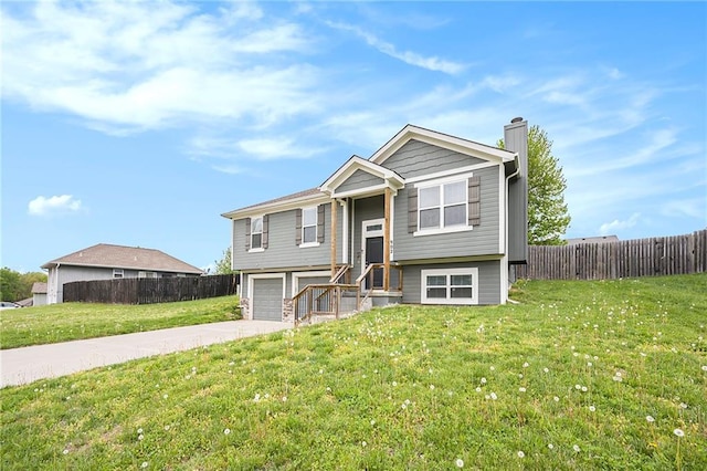 split foyer home featuring a front yard, fence, driveway, and a chimney