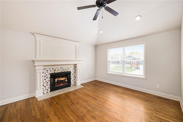 unfurnished living room featuring visible vents, a tiled fireplace, baseboards, wood finished floors, and vaulted ceiling