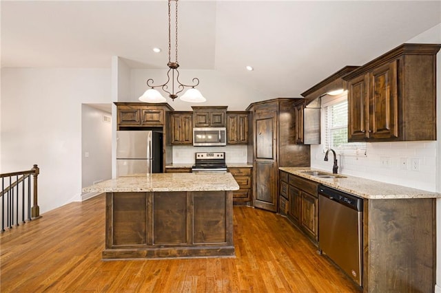 kitchen with lofted ceiling, dark brown cabinetry, a sink, backsplash, and stainless steel appliances