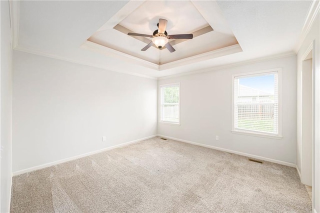 empty room featuring visible vents, ornamental molding, carpet, and a tray ceiling