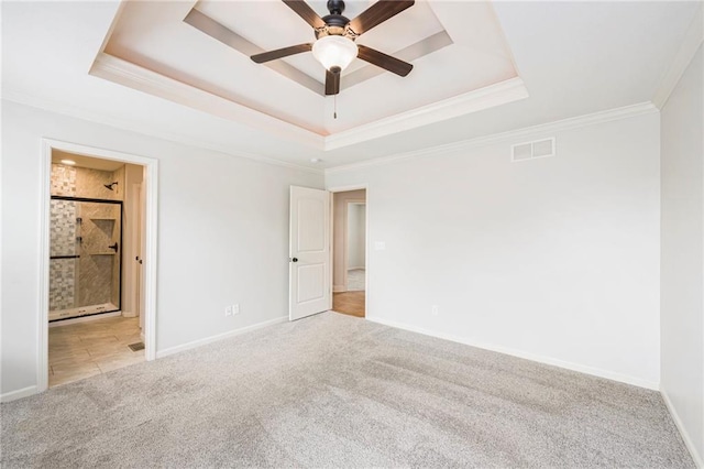 unfurnished bedroom with a raised ceiling, carpet floors, baseboards, visible vents, and ornamental molding