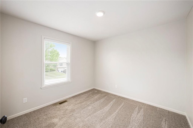 carpeted spare room featuring visible vents and baseboards