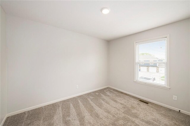 carpeted empty room with visible vents and baseboards
