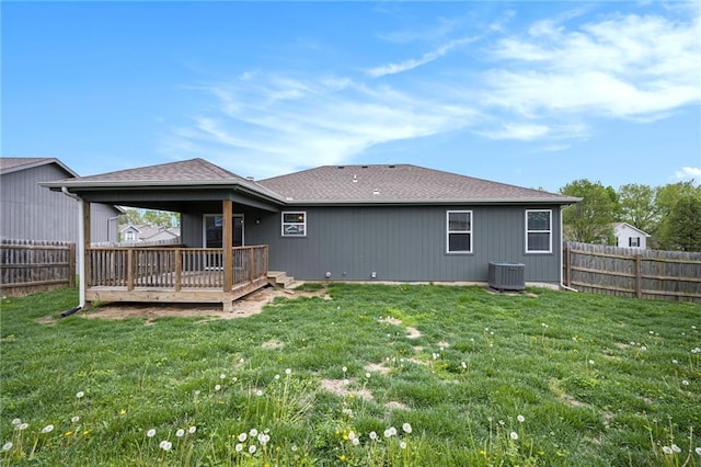 rear view of property with a fenced backyard, a wooden deck, a lawn, and central AC