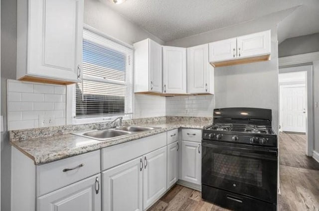 2922 Bales Ave, Kansas City, MO 64128 - kitchen featuring a sink, white cabinetry, black gas range, and light countertops