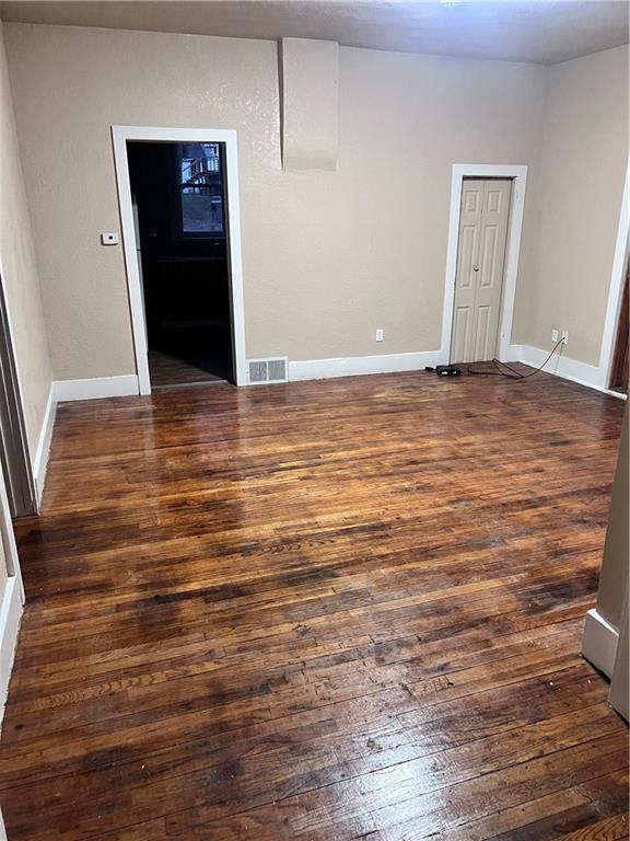 spare room with visible vents, dark wood-style flooring, and baseboards