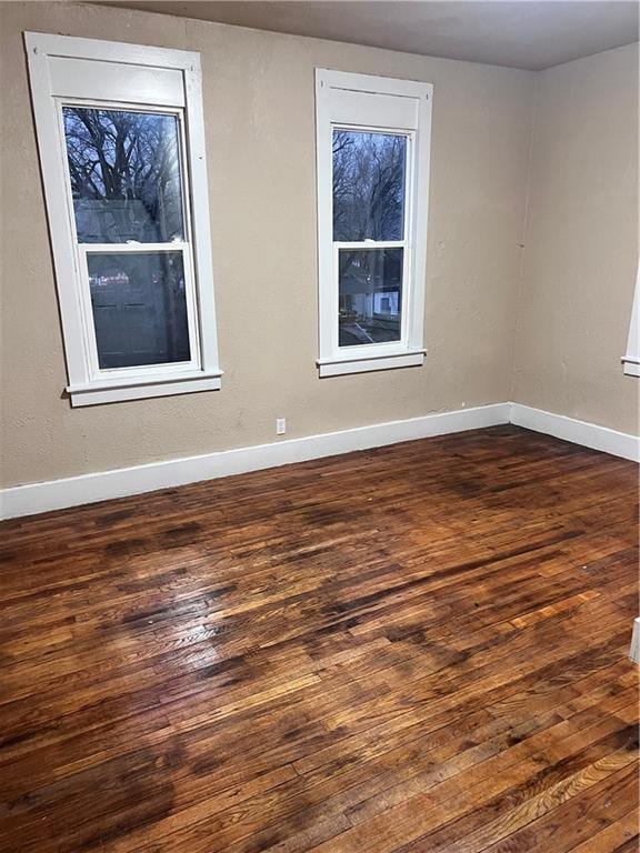 spare room featuring wood-type flooring and baseboards
