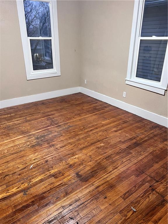 unfurnished room with dark wood-type flooring and baseboards