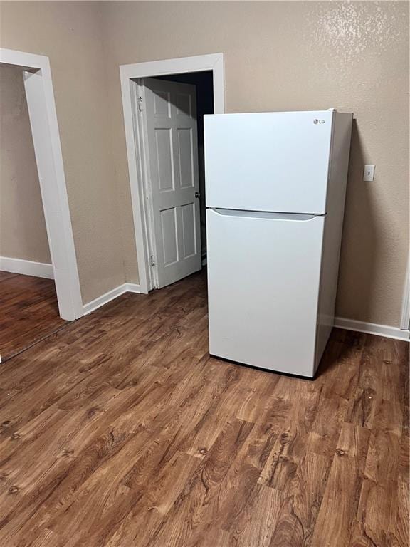 kitchen featuring wood finished floors, freestanding refrigerator, and baseboards