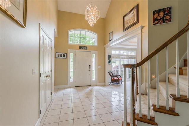 entryway featuring high vaulted ceiling, stairs, a chandelier, baseboards, and light tile patterned flooring