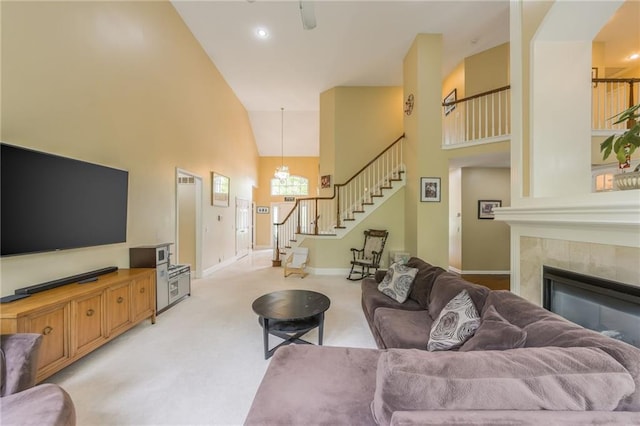 living room featuring stairway, high vaulted ceiling, baseboards, a chandelier, and a tile fireplace