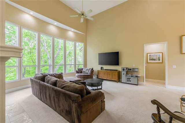 living room featuring light carpet, a high ceiling, ceiling fan, and baseboards