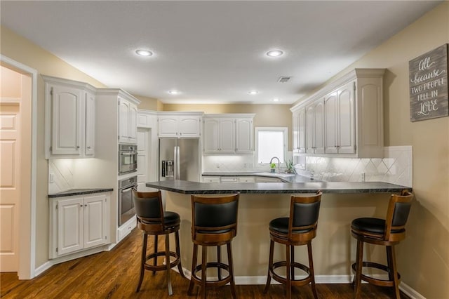 kitchen featuring stainless steel refrigerator with ice dispenser, a peninsula, dark wood-style floors, decorative backsplash, and recessed lighting