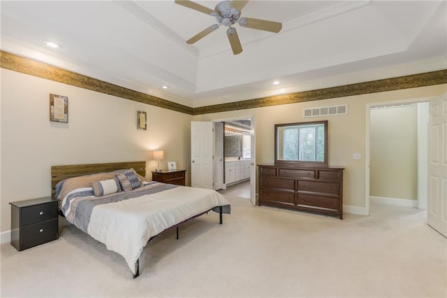 bedroom featuring a raised ceiling, light carpet, recessed lighting, baseboards, and ensuite bathroom