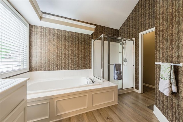 bathroom featuring wallpapered walls, healthy amount of natural light, a garden tub, wood finished floors, and vaulted ceiling
