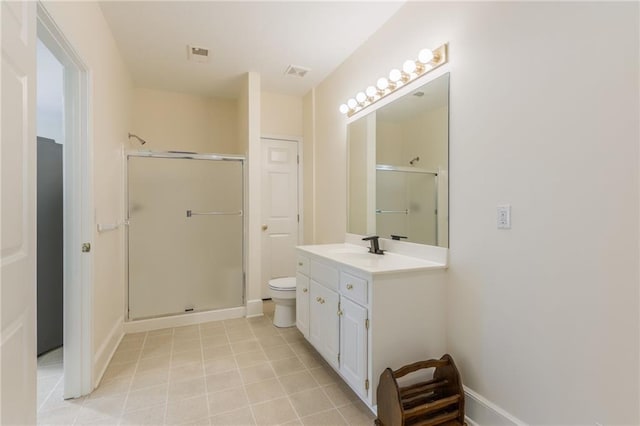 bathroom with a stall shower, toilet, vanity, baseboards, and tile patterned floors