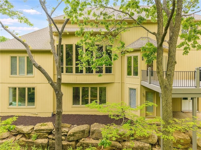 back of property featuring roof with shingles and a balcony