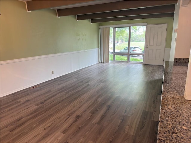 spare room with dark wood-style flooring, wainscoting, and beam ceiling