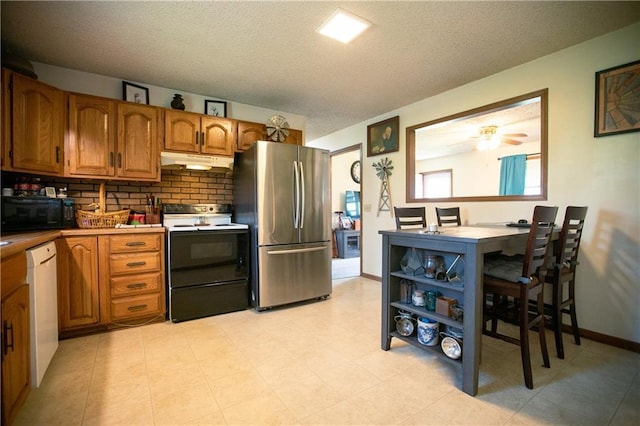 kitchen with black microwave, white dishwasher, freestanding refrigerator, under cabinet range hood, and electric stove