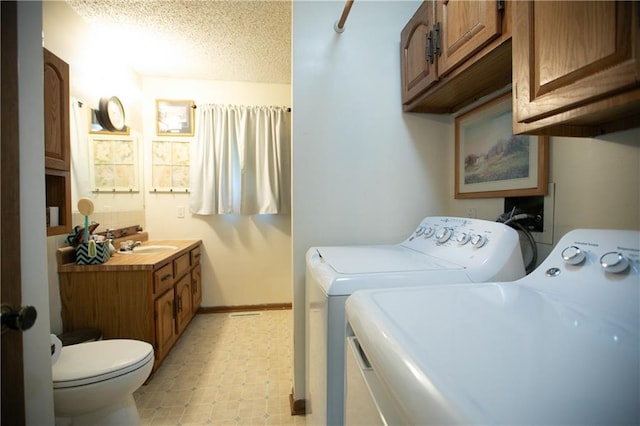laundry area featuring separate washer and dryer, laundry area, a sink, baseboards, and a textured ceiling