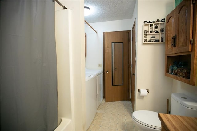 full bathroom with tile patterned floors, a textured ceiling, toilet, and washer and clothes dryer