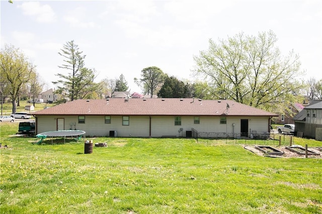 rear view of house featuring a lawn, central AC unit, a vegetable garden, and a trampoline
