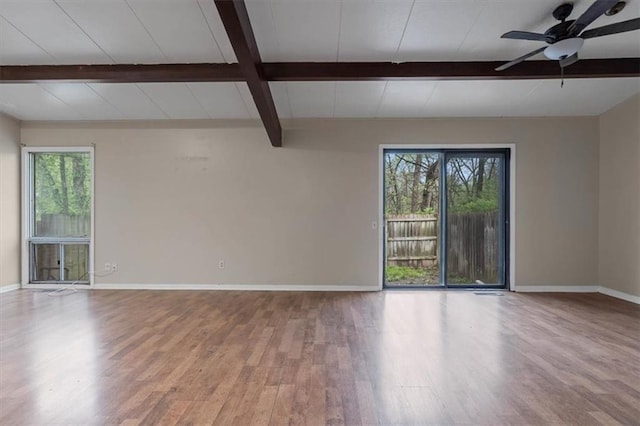 unfurnished room featuring beam ceiling, wood finished floors, ceiling fan, and baseboards
