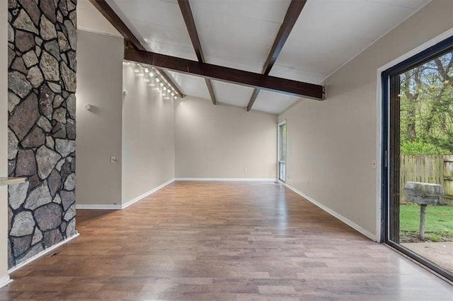 unfurnished living room featuring beam ceiling, baseboards, wood finished floors, and a wealth of natural light