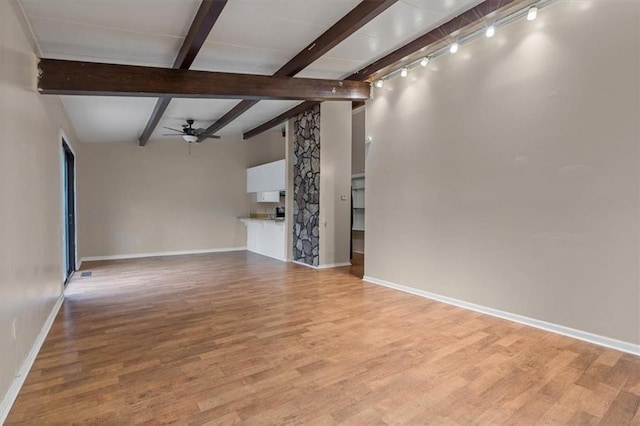 unfurnished living room featuring beam ceiling, a ceiling fan, light wood-style flooring, and baseboards