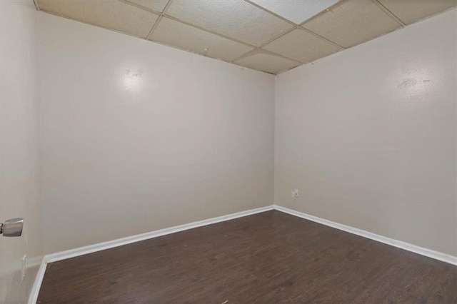 empty room featuring dark wood finished floors, baseboards, and a drop ceiling