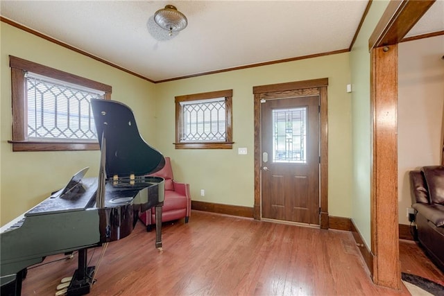 foyer entrance featuring baseboards, ornamental molding, and light wood-style floors