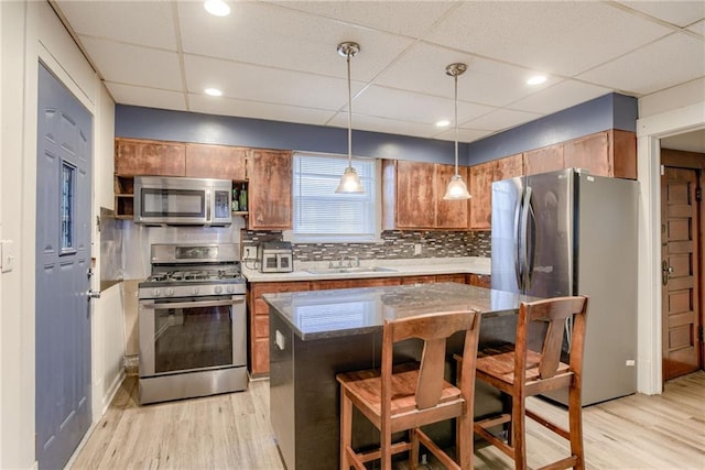 kitchen featuring a drop ceiling, stainless steel appliances, light wood finished floors, and a sink