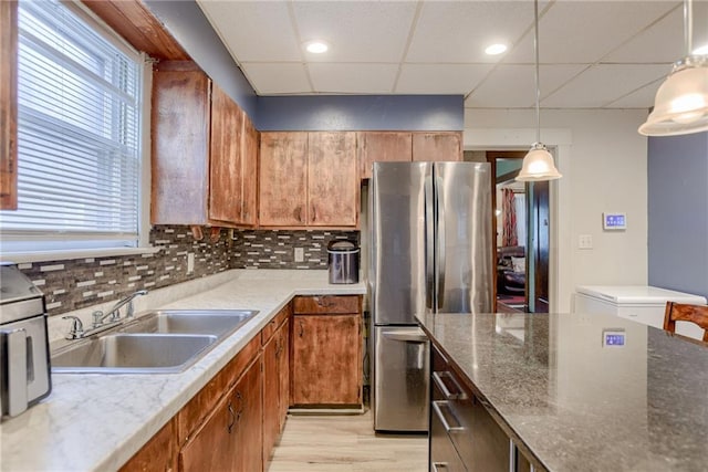 kitchen featuring tasteful backsplash, freestanding refrigerator, a drop ceiling, a sink, and light wood-type flooring