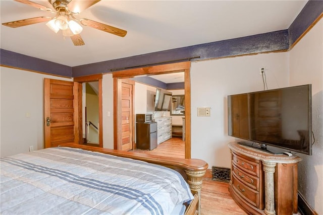 bedroom with a ceiling fan, light wood-style flooring, and freestanding refrigerator