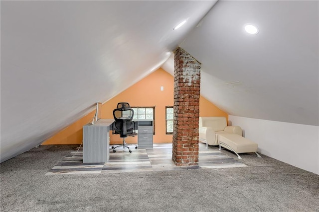 unfurnished office featuring ornate columns, carpet floors, and lofted ceiling