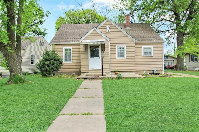 bungalow with a chimney, a front yard, and roof with shingles