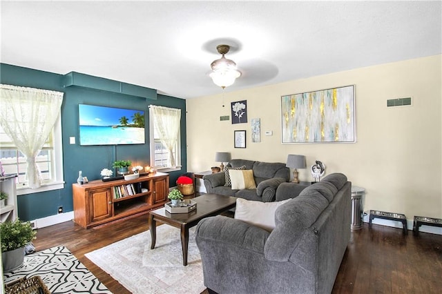 living area featuring a ceiling fan, visible vents, wood finished floors, and baseboards