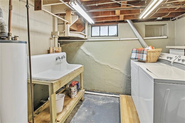 laundry area with gas water heater, washing machine and clothes dryer, laundry area, and a sink